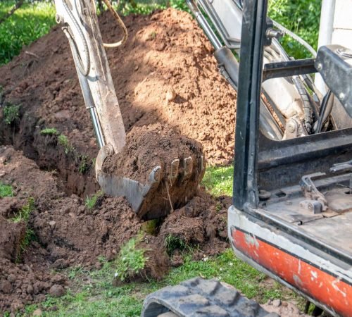 Construction waste removal with excavator clearing building rubble, concrete, bricks, and site debris.