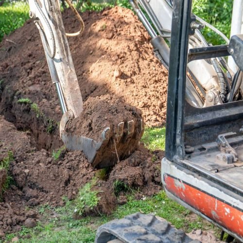 Construction waste removal with excavator clearing building rubble, concrete, bricks, and site debris.