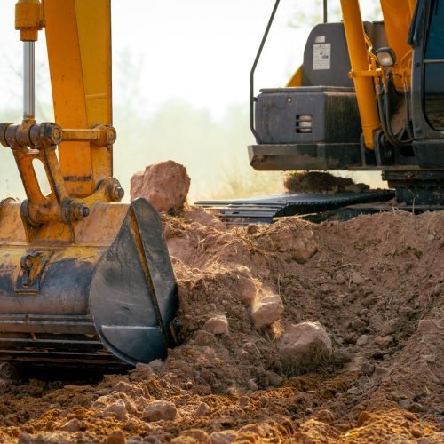 Closeup bucket of backhoe digging the soil at construction site. Crawler excavator digging on demolition site. Excavating machine. Earth moving equipment. Excavation vehicle. Construction business.
